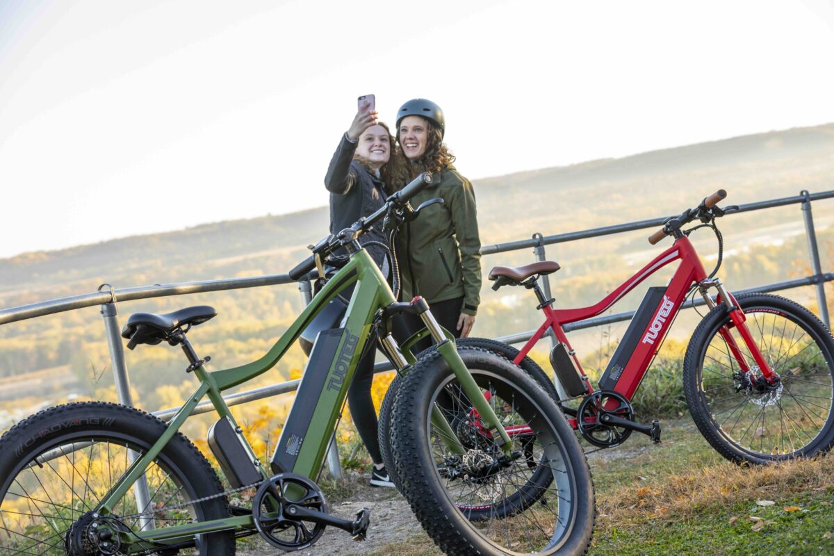 two women taking a selfie by red and green ebikes