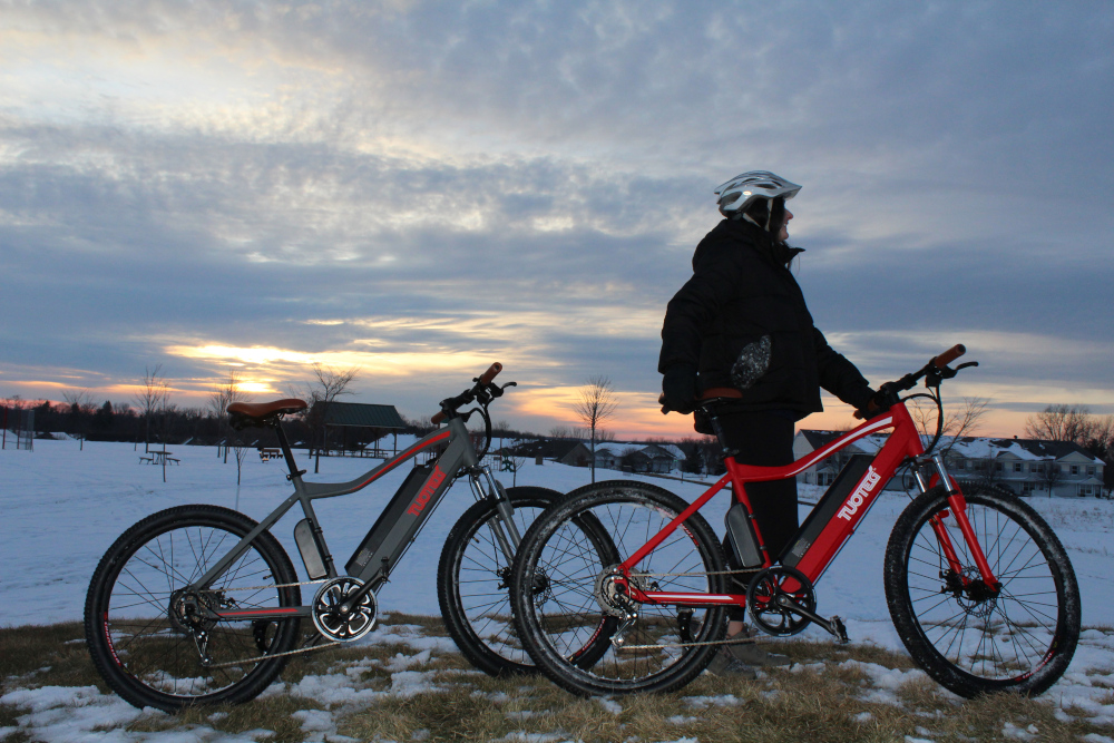 two electric bikes in snow with sunset